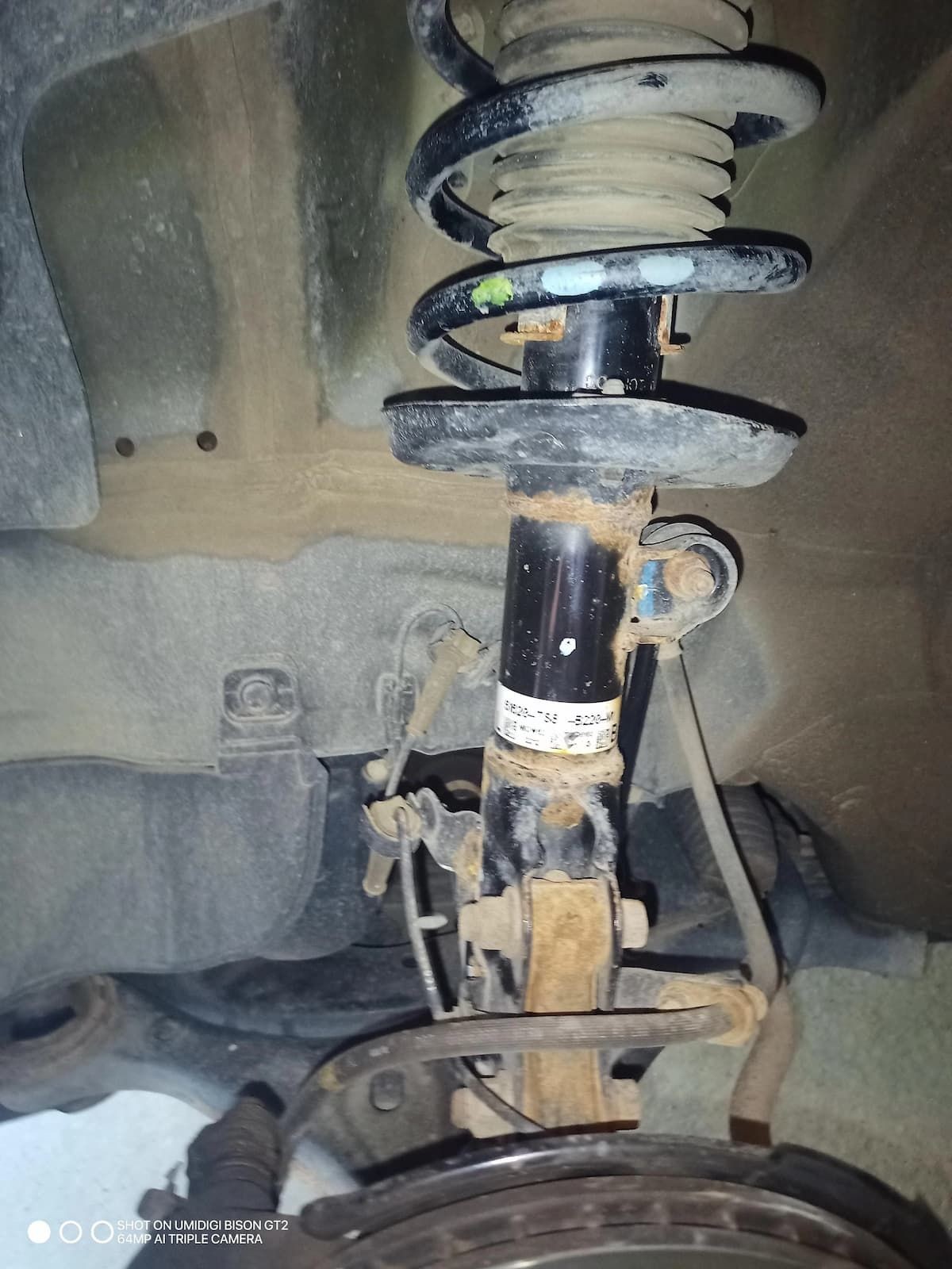 Front strut and coil spring assembly on a Honda suspension, showing the strut mount, spring, and control arm.